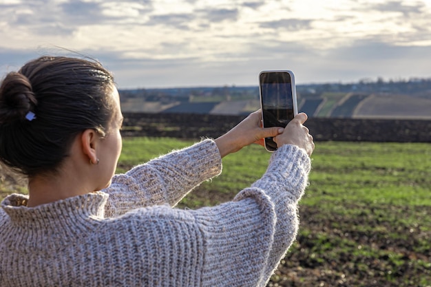 Mujer joven hace una foto del campo por teléfono inteligente