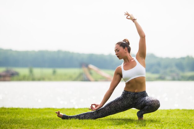 Mujer joven hacer pose de yoga en el parque por la mañana con luz solar