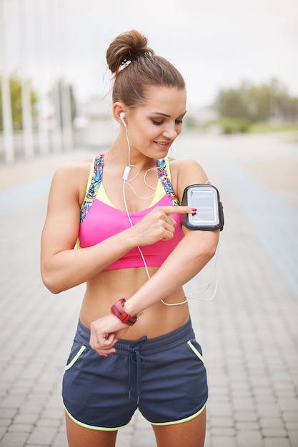 Foto gratuita mujer joven haciendo ejercicio al aire libre. lo que necesito mientras corro es buena música.