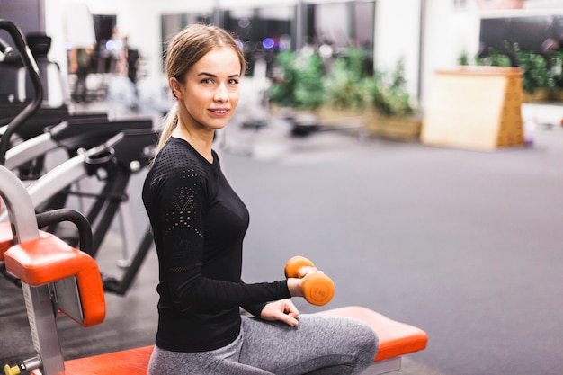 Mujer joven haciendo ejercicio con pesas en el gimnasio