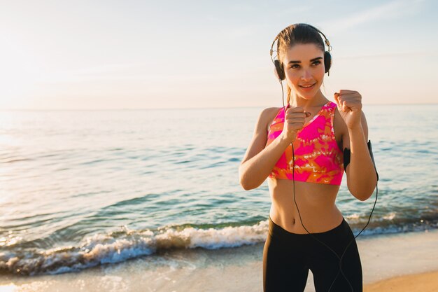 Mujer joven haciendo ejercicios deportivos en la playa del amanecer en la mañana