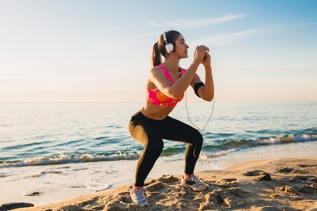 Mujer joven haciendo ejercicios deportivos en la playa del amanecer en la mañana