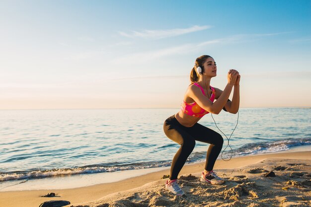 Mujer joven haciendo ejercicios deportivos en la playa del amanecer en la mañana