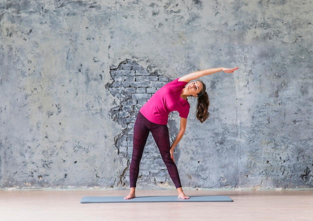 Mujer joven haciendo ejercicios de estiramiento en la clase de yoga