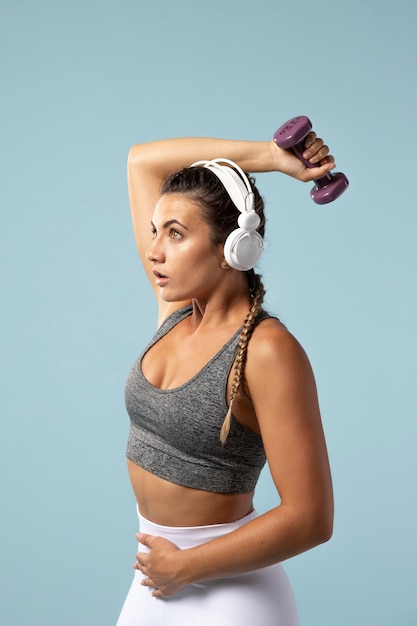 Foto gratuita mujer joven haciendo ejercicios con sus auriculares