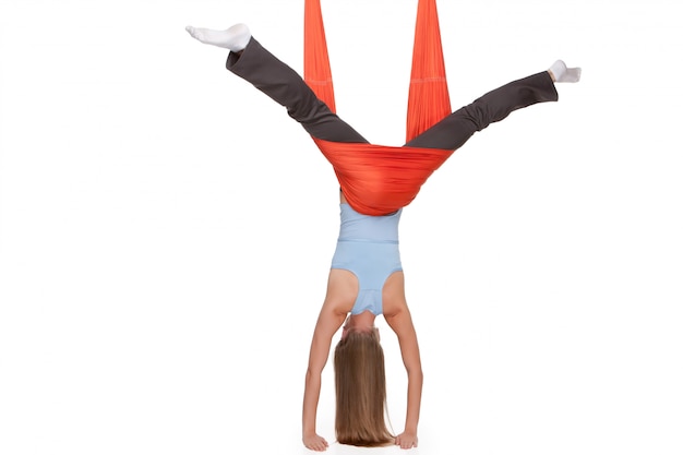 Mujer joven haciendo ejercicios de yoga antigravedad en estiramiento de hilo