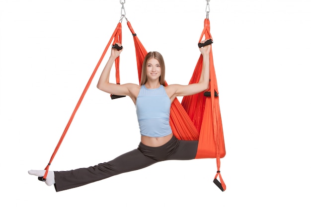 Mujer joven haciendo ejercicios de yoga antigravedad en estiramiento de hilo