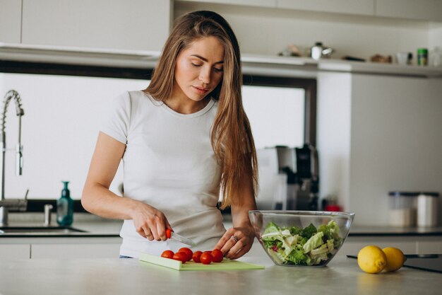 Mujer joven haciendo ensalada en la cocina