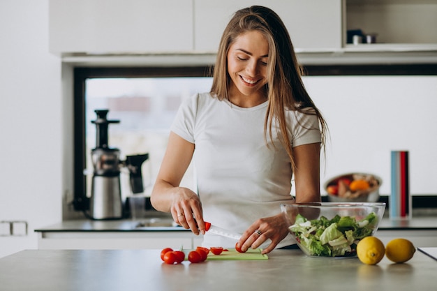 Mujer joven haciendo ensalada en la cocina