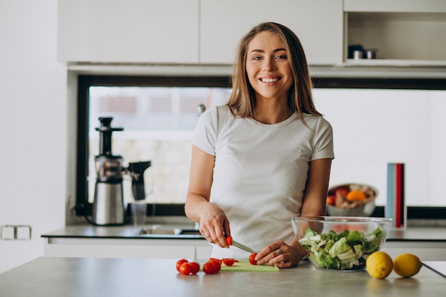 Mujer joven haciendo ensalada en la cocina