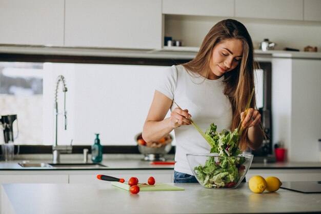 Mujer joven haciendo ensalada en la cocina