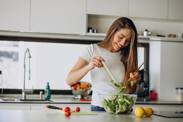 Mujer joven haciendo ensalada en la cocina