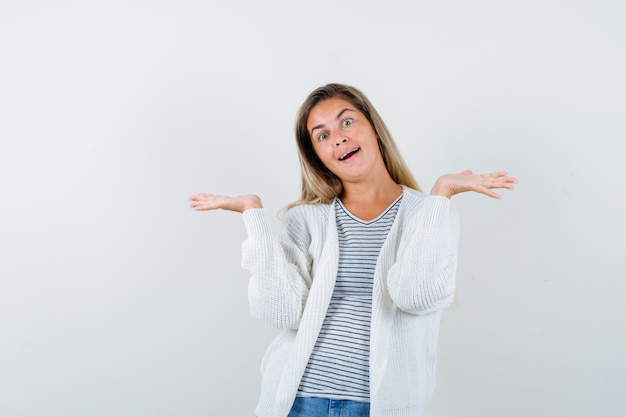 Mujer joven haciendo gesto de bienvenida en camiseta, chaqueta y mirando alegre, vista frontal.