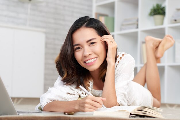 Mujer joven haciendo notas en su cuaderno mirando a la cámara