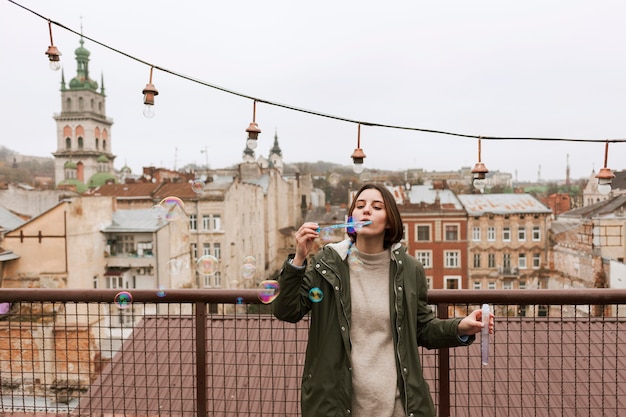 Foto gratuita mujer joven haciendo pompas de jabón