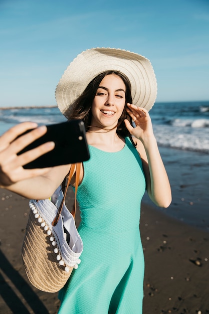 Mujer joven haciendo selfie en la playa