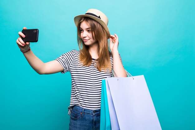 Mujer joven haciendo una selfie en su teléfono inteligente sentado con bolsas de colores para ir de compras