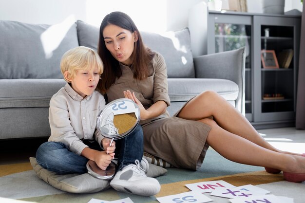 Mujer joven haciendo terapia del habla con un niño rubio