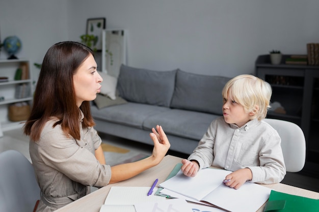 Mujer joven haciendo terapia del habla con un niño