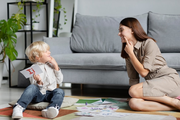 Mujer joven haciendo terapia del habla con un niño