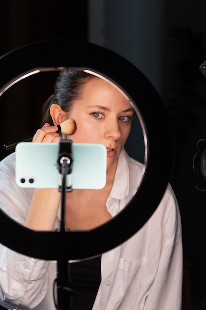 Mujer joven haciendo un vlog de maquillaje con su smartphone