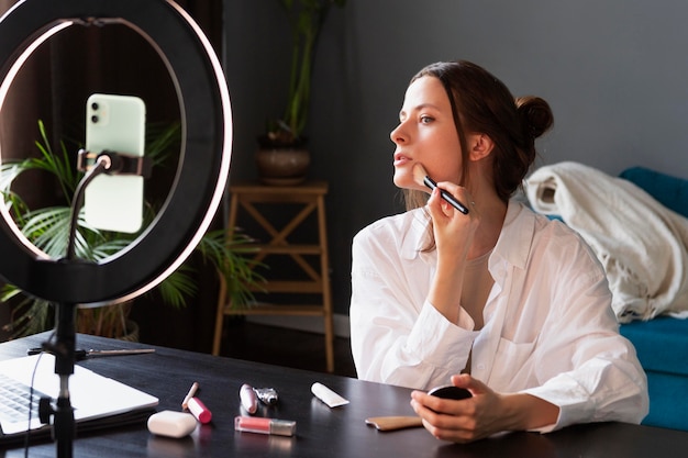 Mujer joven haciendo un vlog de maquillaje con su smartphone