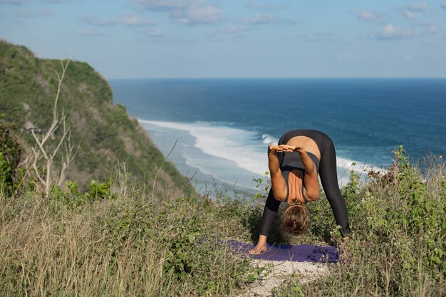 Mujer joven haciendo yoga al aire libre con una increíble vista posterior. Bali. Indonesia.