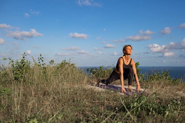 Mujer joven haciendo yoga al aire libre con una increíble vista posterior. Bali. Indonesia.