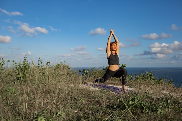 Mujer joven haciendo yoga al aire libre con una increíble vista posterior. Bali. Indonesia.