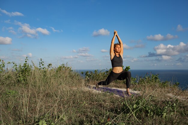 Mujer joven haciendo yoga al aire libre con una increíble vista posterior. Bali. Indonesia.