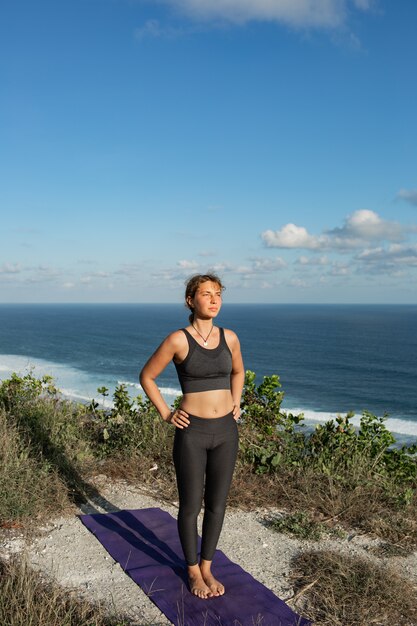 Mujer joven haciendo yoga al aire libre con una increíble vista posterior. Bali. Indonesia.