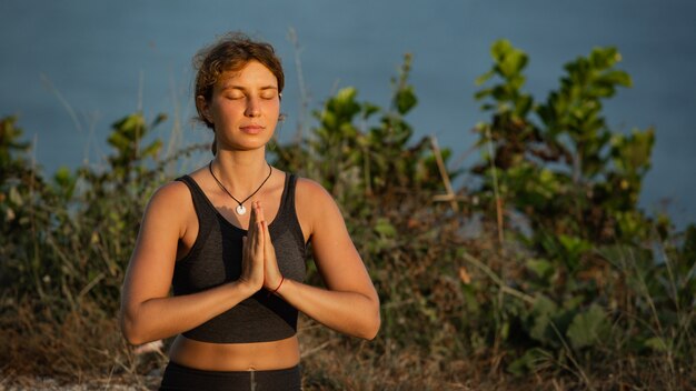 Mujer joven haciendo yoga al aire libre con una increíble vista posterior. Bali. Indonesia.