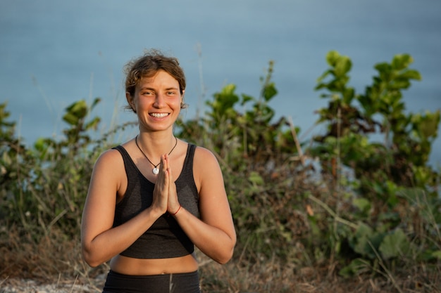 Mujer joven haciendo yoga al aire libre con una increíble vista posterior. Bali. Indonesia.