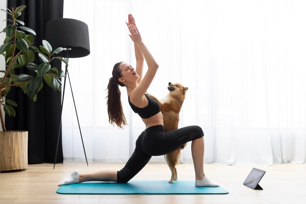 Mujer joven haciendo yoga junto a su perro