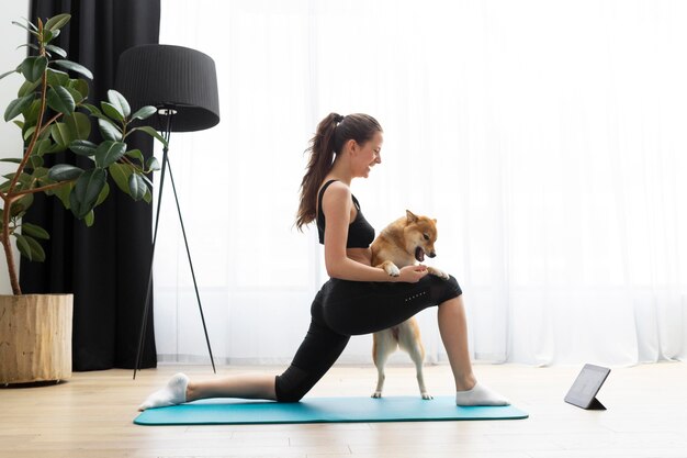 Mujer joven haciendo yoga junto a su perro