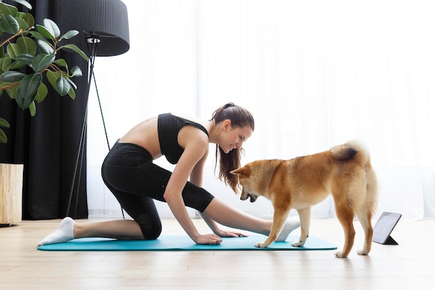 Mujer joven haciendo yoga junto a su perro