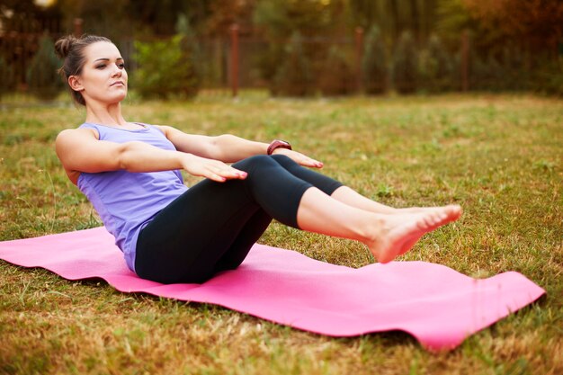 Mujer joven haciendo yoga en el parque. Un buen estiramiento ayuda a evitar el dolor muscular