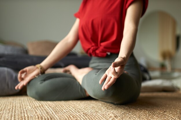 Mujer joven haciendo yoga en posición de loto en casa