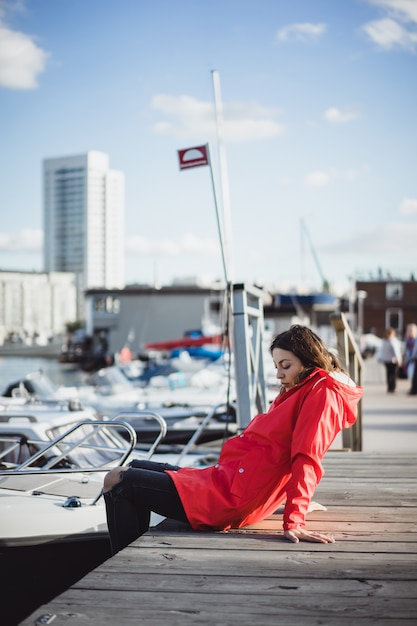 Mujer joven hermosa en una capa roja en el puerto del yate. Estocolmo, Suiza