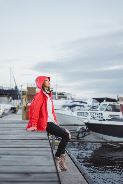 Mujer joven hermosa en una capa roja en el puerto del yate. Estocolmo, Suiza