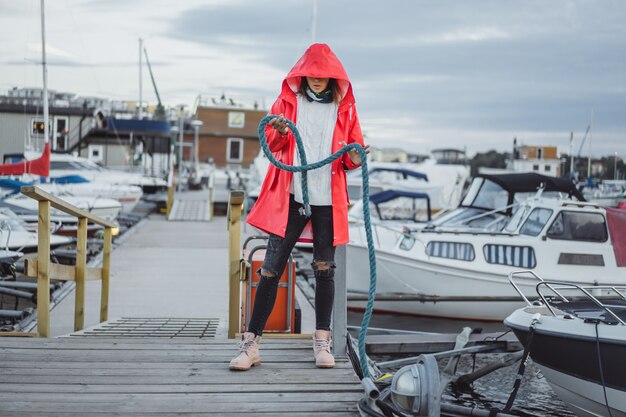 Mujer joven hermosa en una capa roja en el puerto del yate. Estocolmo, Suiza