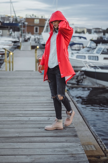 Mujer joven hermosa en una capa roja en el puerto del yate. Estocolmo, Suiza