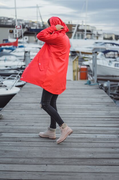 Mujer joven hermosa en una capa roja en el puerto del yate. Estocolmo, Suiza