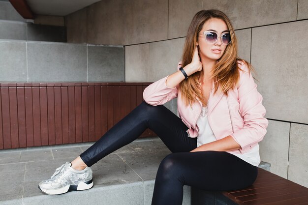 Mujer joven hermosa con estilo hipster en chaqueta de cuero rosa