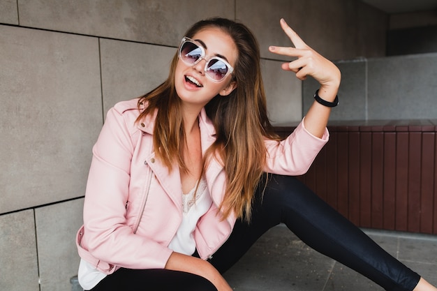 Mujer joven hermosa con estilo hipster en chaqueta de cuero rosa