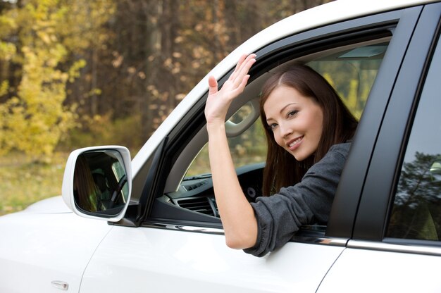 Mujer joven hermosa exitosa en el coche nuevo - al aire libre