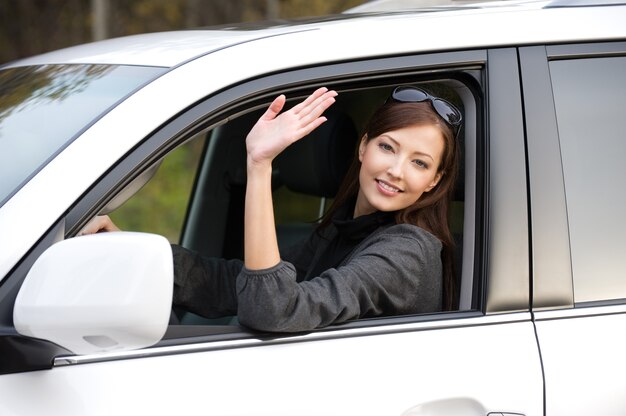 Foto gratuita mujer joven hermosa exitosa en el coche nuevo