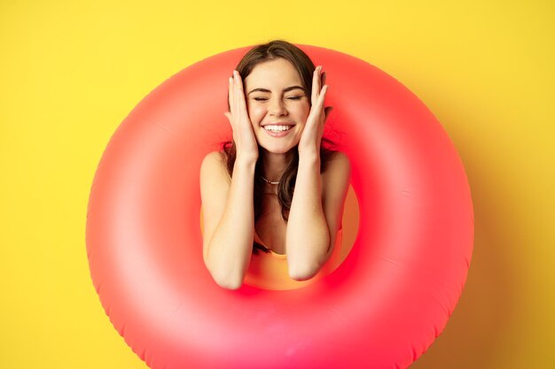 Mujer joven hermosa feliz que se relaja en las vacaciones de verano que lleva el anillo rosado de la nadad...