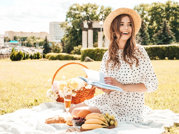 Mujer joven hermosa hipster en vestido de verano de moda y sombrero. Mujer despreocupada haciendo picnic afuera.