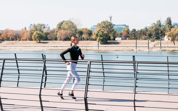 Mujer joven hermosa juguetona que corre en el aire libre